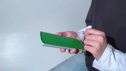 Person views scrolls the screen of a smartphone device. The screen is green Stock Footage 280336236