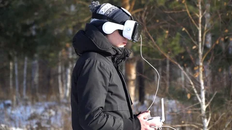 A person in virtual reality glasses controls a drone on the background of the fo Stock Footage 85994782