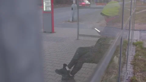 A person waits at a bus stop, looking at their smartphones reflection Stock Footage 311118048