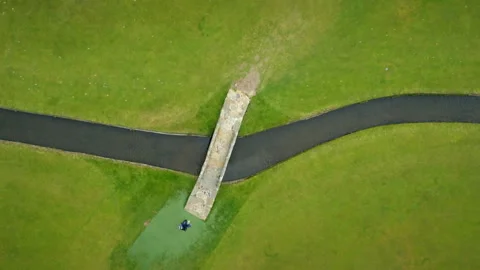 Person walking across a stone bridge over a stream aerial view Video stock 336792835