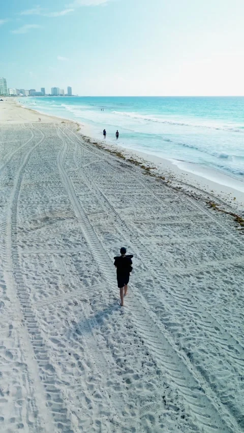 Person walking alone on a vast white sand beach seen from above Stock Footage 342090301