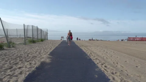 Person walking along an accessibility mat to the ocean Stock Footage 331801696