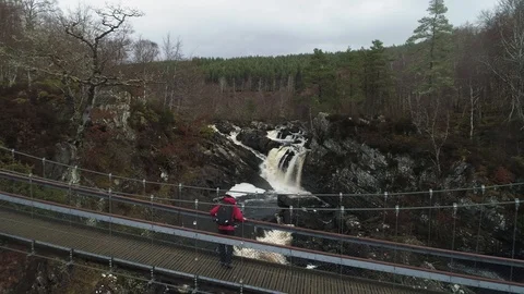 Person walking and looking at view of huge waterfall, Scotland drone aerial 4K Stock Footage 104579172