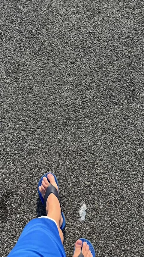 Person walking on asphalt road wearing blue flip flops Stock Footage 341664093