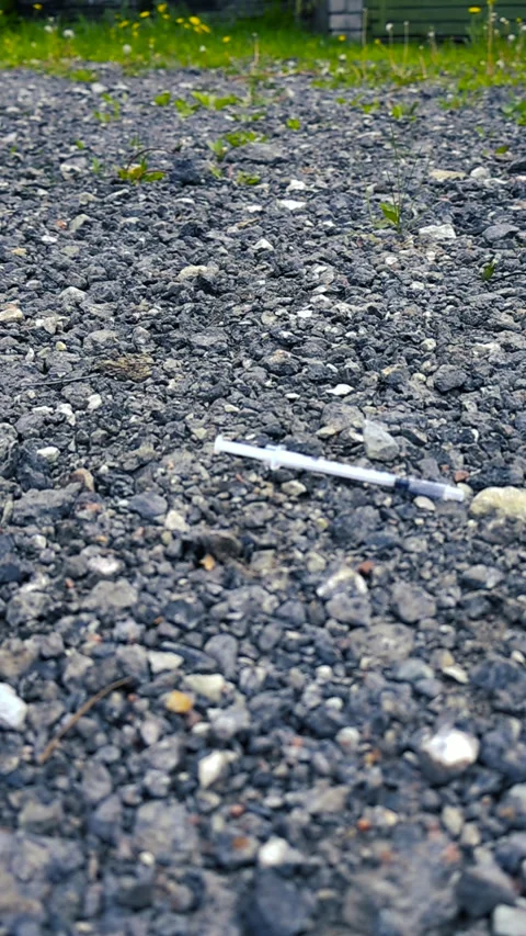 Person Walking Away after Dropping a Used Syringe on the Ground Stock Footage 340849876