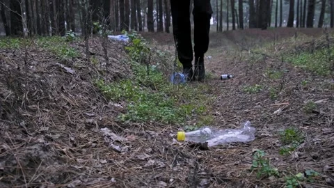 Person Walking Away Through Littered Forest Path with Bottles Stock Footage 324826201