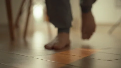Person walking barefoot on a smooth floor in a warm cozy setting during the Stock Footage 323870925