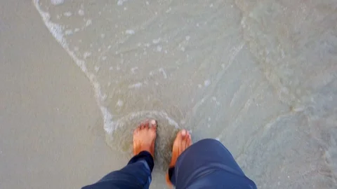 A person walking at the beach with waves gently crushing to the feet Vídeos de archivo 121389316