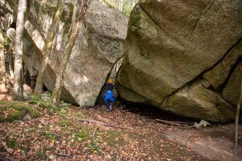 A person walking between two large boulders. Stock Photos