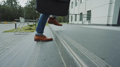 Person walking up concrete steps with briefcase in a city park setting 스톡 동영상 285930247