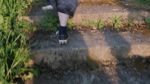 Person walking down stone steps surrounded by greenery at sunset Stock Footage 306393117