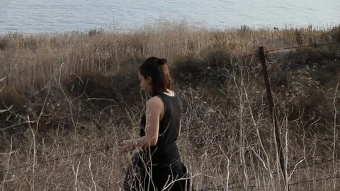 Person walking downhill next to barb wired fence Stock Footage 83133031