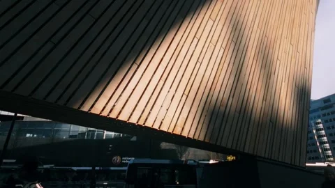 Person walking past unique architectural facade with dramatic sun shadows in Stock Footage 334340772