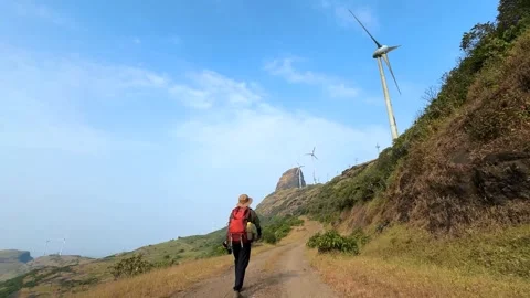 Person walking on a path, hiking in the mountains, wind turbines Stock Footage 286734877