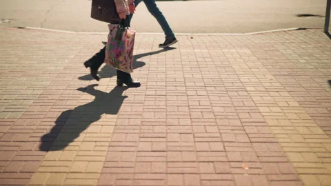 Person walking on sidewalk with shadow in sunlight, close-up view Stock Footage 305532108