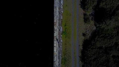 Person Walking On Straight Road Next To Water Reservoir 2 [Drone Footage] Stock Footage 88819827