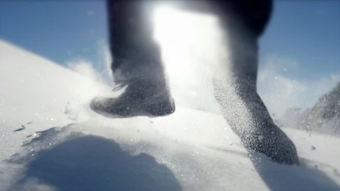 Person walking though deep snow in mountain range environment Stock Footage 86856412