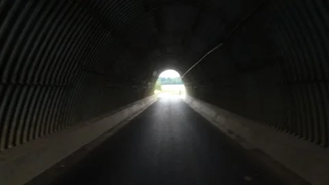 Person Walking Through Dark Cave Tunnel Toward Natural Light Stock Footage 274238681