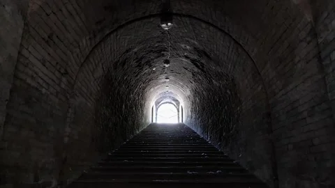 Person walking through a dark tunnel towards light Stock Footage 341314948