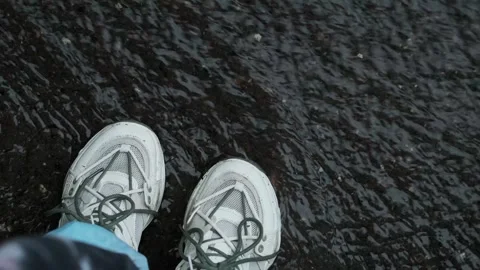 Person walking through a puddle, promoting waterproof and breathable clothing, s Stock Footage 277643179
