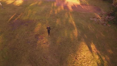 Person walking thru patch of grass at sunset near the beach. Stock Footage 210398369