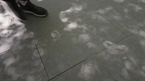 Person Walking on Tiled Pathway with Subtle Shade Patterns Stock Footage 315013151