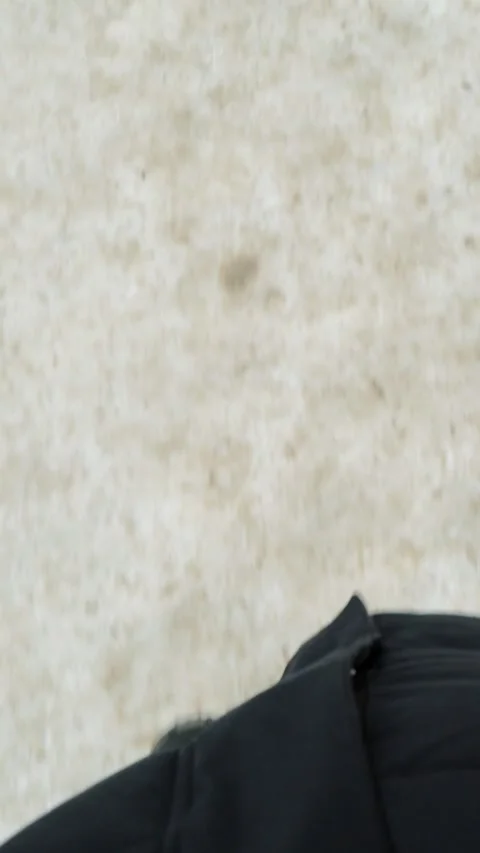 Person walks forward across bright white snow in black winter boots and dark Stock Footage 346774385