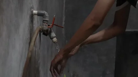 Person washes hands under a simple outdoor tap Stock Footage 340900730