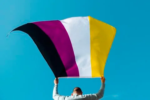 Person waving a non-binary pride flag Stock Photos