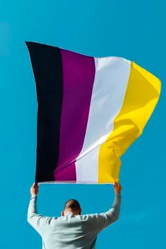 Person waving a non-binary pride flag Stock Photos