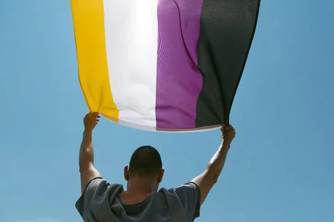 Person waving a non-binary pride flag Stock Photos