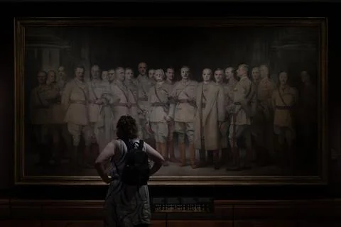 A person wearing a backpack is observing a large painting. The painting dep.. Stock Photos
