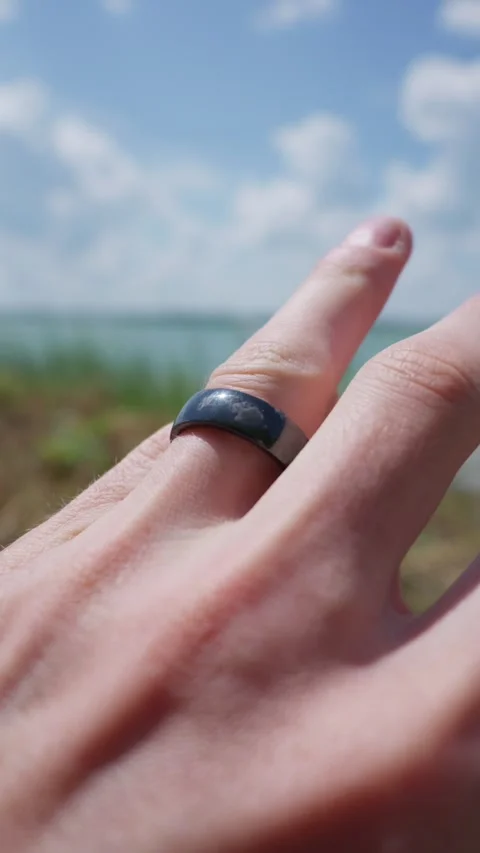 Person Wearing Black Smart Ring on Finger Against Sunny Sky Background Stock Footage 341987506