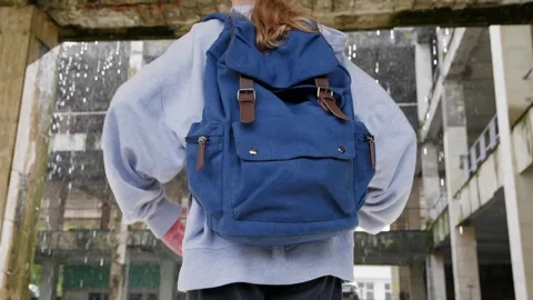 Person wearing blue backpack standing in urban alley, overhead shot Stock Footage 346799335