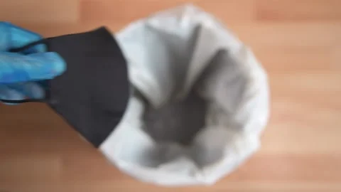 Person Wearing Gloves Drops Black fabric Mask Into Bin Stock Footage 157173853