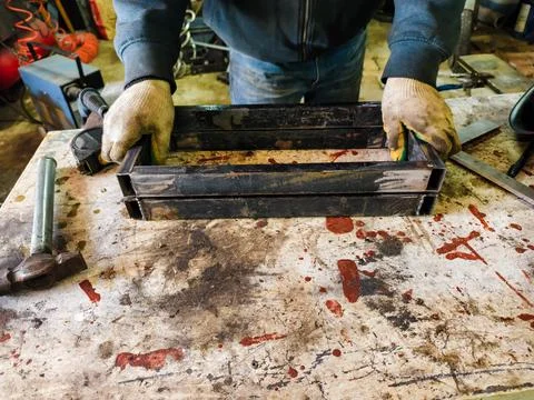 Person wearing protective gloves assembling metal profiles on a weathered Stockfoto's