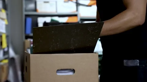 A person wearing a watch and ring is organizing documents in a cardboard Stock Footage 278973631