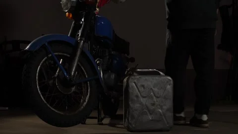 Person wearing work gloves walking past a blue 1970s classic motorcycle with a Stock Footage 340431254