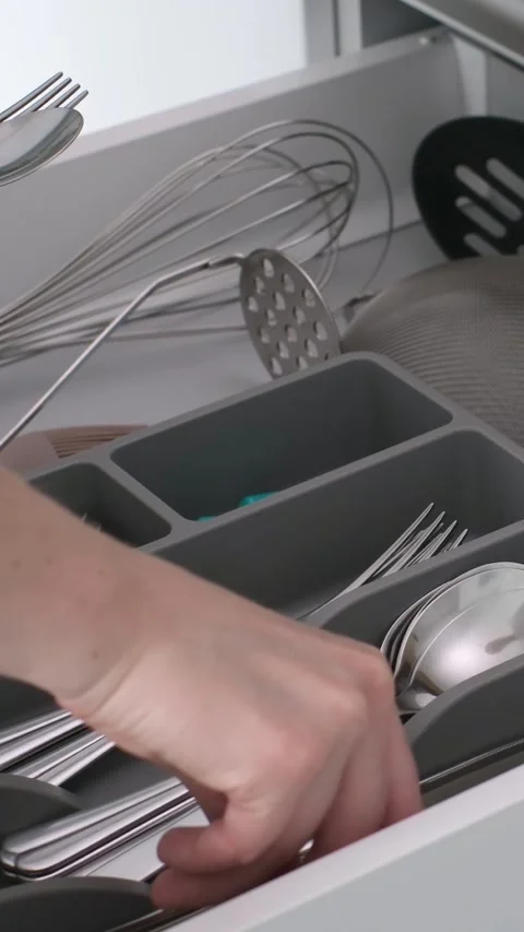 A person in white attire is engaged in retrieving cutlery from a neatly Stock Footage 315660911