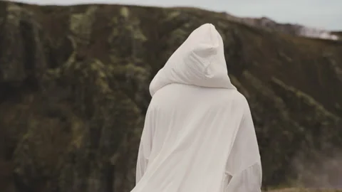 Person White Robe Sways With the Wind as He Wanders Towards a Mountain Range Stock Footage 155758902