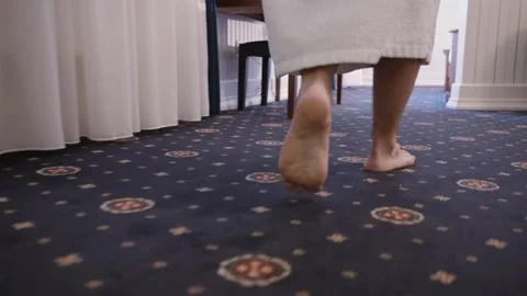 A person in a white towel stands on a patterned carpet. The focus is on the bare Stock Footage 263029967