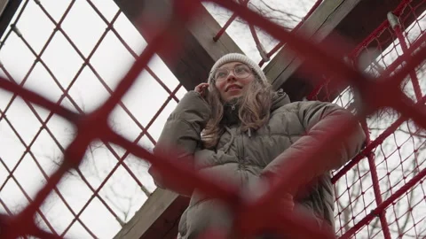 Person in winter attire behind net. Low angle view through ropes captures candid Stock Footage 342285787