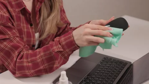 Person wipes black mouse using disinfectant spray and cloth. Closeup of lady Stock Footage 347878593