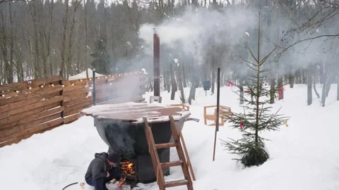 Person in work clothes lighting a large outdoor hot tub Stockbeeldmateriaal 329107899
