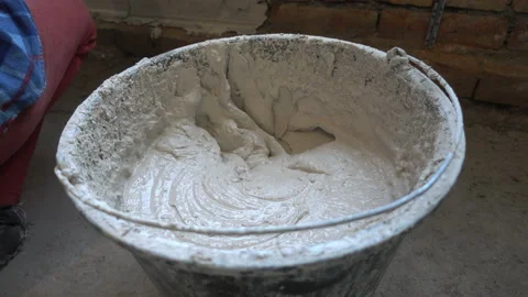 Person in work gloves ( hand in the frame) holds a trowel with plaster and Stock Footage 137915899