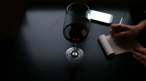Person working and taking notes with a glass of wine Stock-Footage 58195530