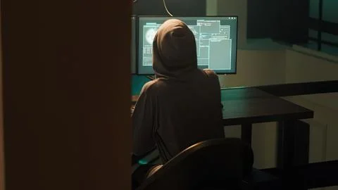 Person working on computer in dim office room Stock Photos