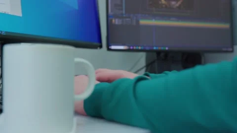 A person is working at a computer with a white cup of coffee on a desk in the fo Stock Footage 270402386