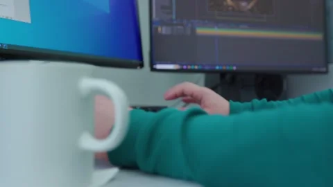 A person is working at a computer with a white cup of coffee on a desk Stock Footage 274041460