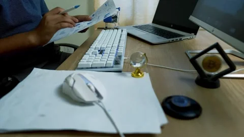 Person working at a desk with computer, keyboard, and documents Stock Footage 315981722